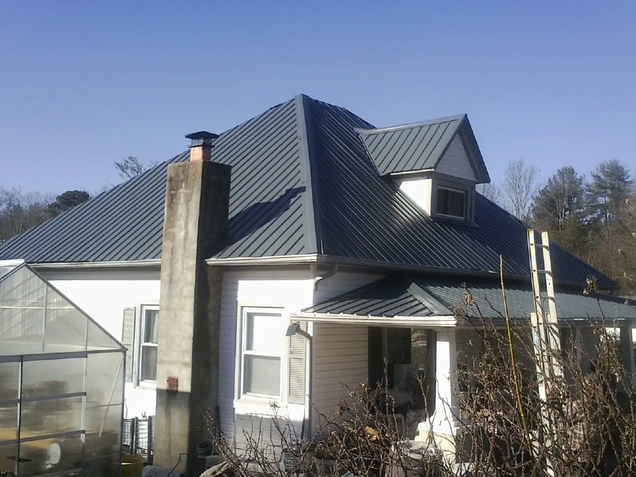 Dark blue standing seam metal roof on a white farmhouse with dormer — Slate & Tile Roof Repair by Roofing Brothers in Makoti