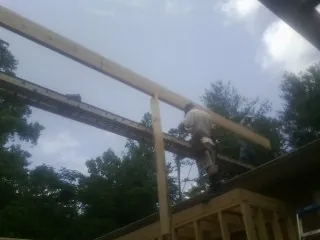 Carpenter setting a ridge beam over a new addition frame — Ice Dam Removal by Roofing Brothers in Makoti