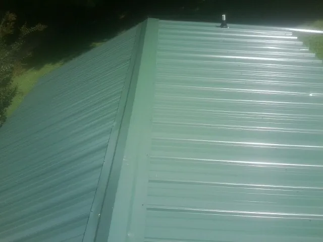 New green metal panels meeting at the ridge of a roof — Flat Roof Repair work by our crew in Makoti
