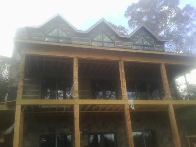 Dormers and porch framing on a large log home under construction — Roof Coating work by our crew in Makoti