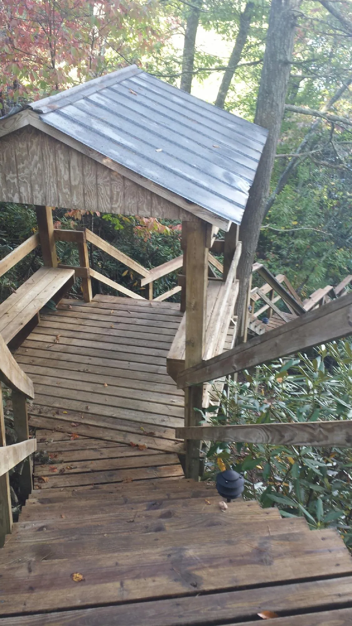 Metal roofed shelter over wooden steps on a wooded walkway — Skylight Repair & Installation work by our crew in Makoti